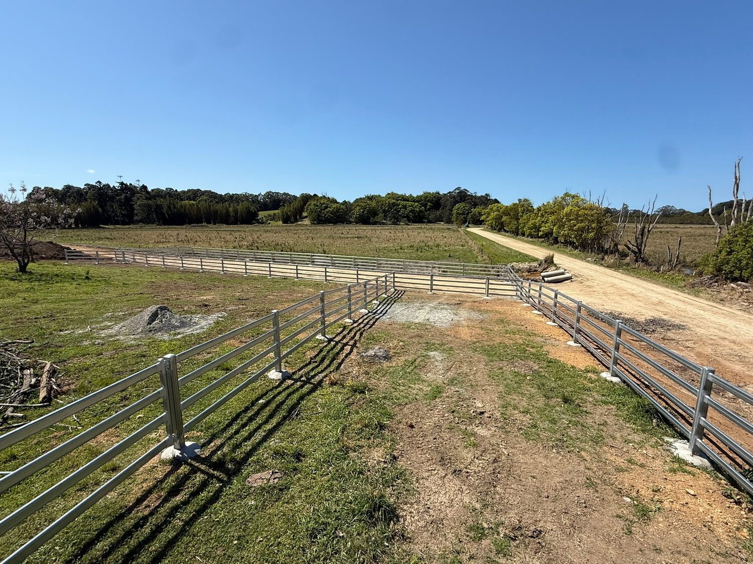 Galvanised cattle rail fencing across a paddock